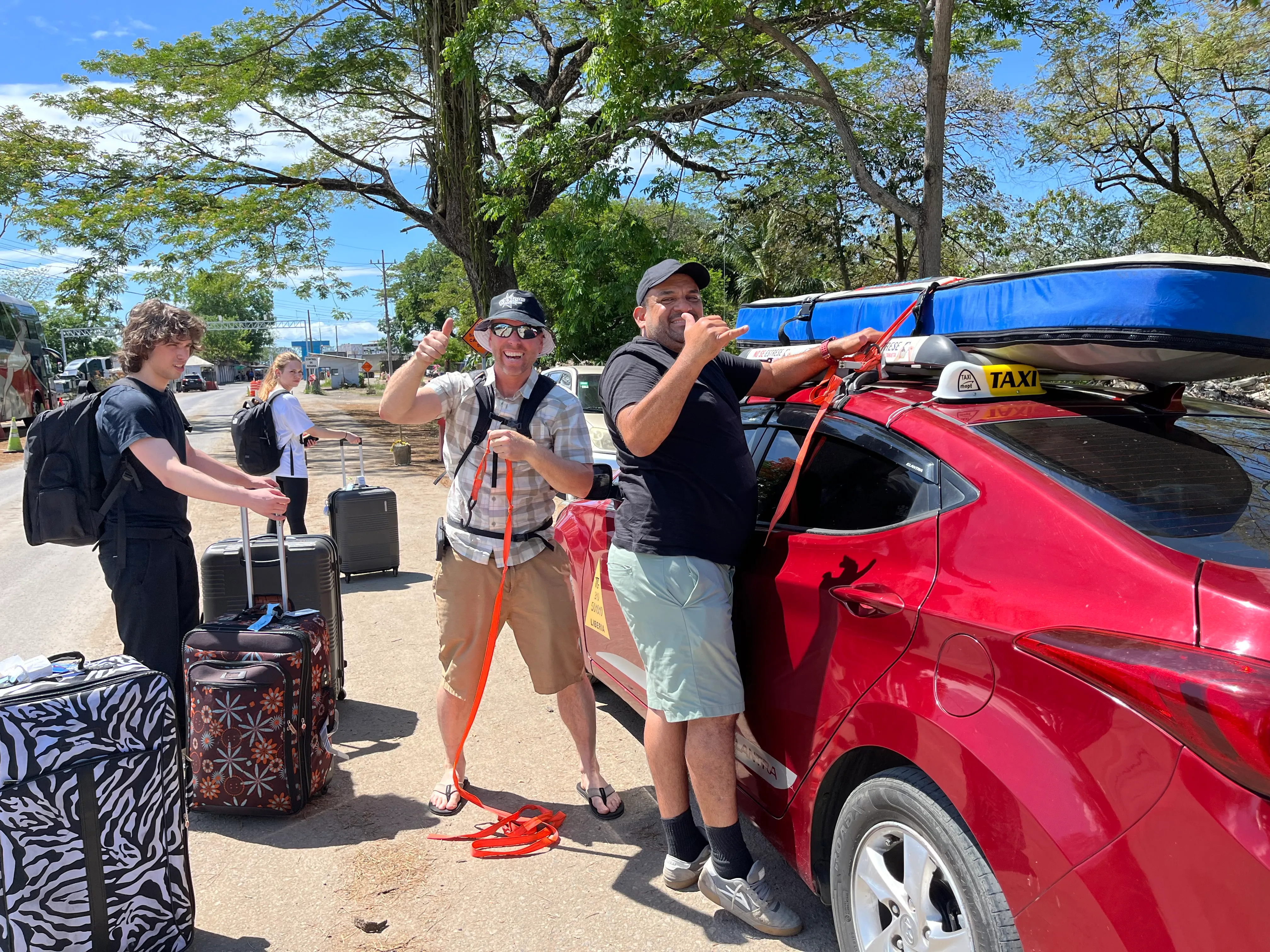 Friends loading surfboards onto a red taxi
